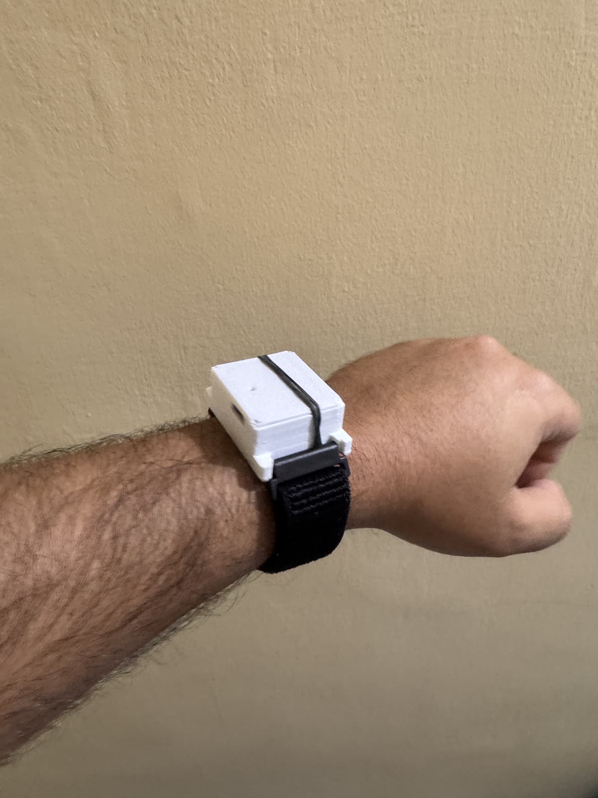 White 3D-printed Keepshake prototype secured to a wrist with a black strap